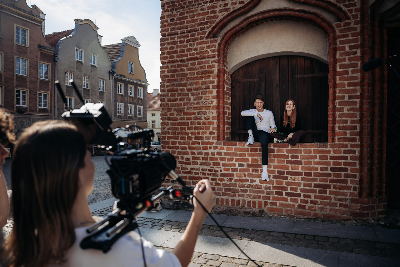 Młodzi uczestnicy warsztatów filmowych podczas pracy na planie filmowym w Olsztynie. Kamera, światła i wspólna realizacja krótkiego filmu w ramach WAMA Film Festival.